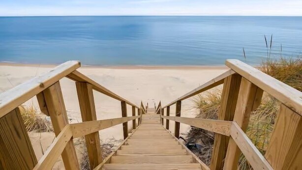 Eine Holztreppe führt zu einem Strand mit freiem Blick auf das Meer.
