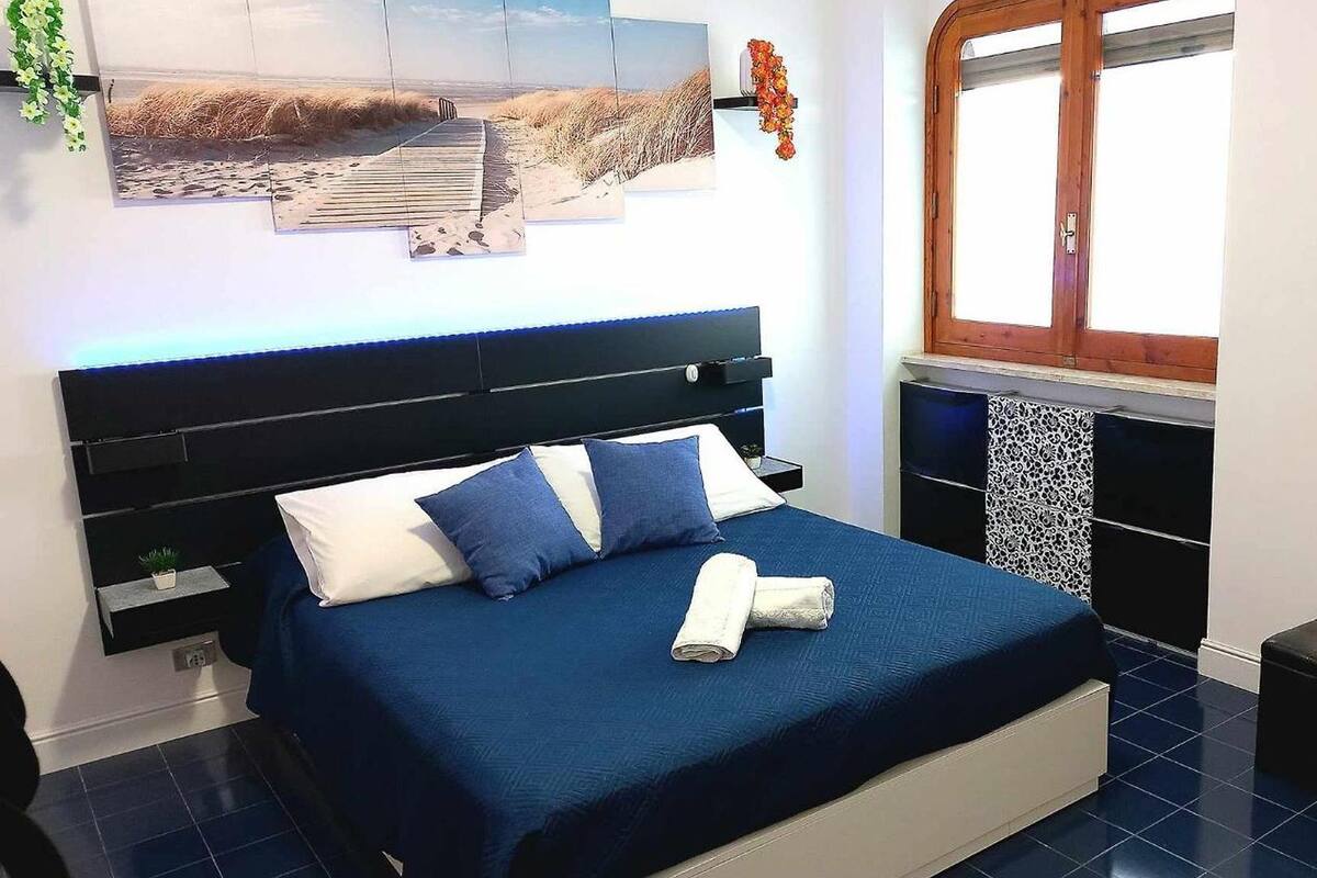 Ein Schlafzimmer mit Bett, Nachttisch, Schminktisch und einem Fenster.