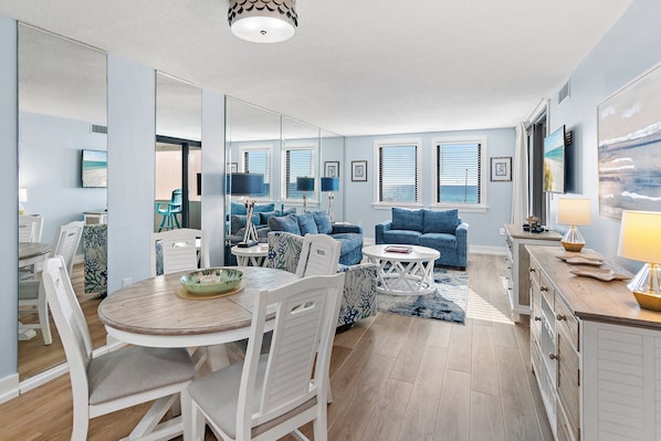 A modern living room with a dining area, featuring a round table, chairs, sofas, and a coffee table.