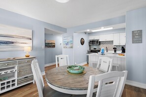 A modern kitchen with white cabinets, a microwave, and a sink.