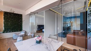 A modern interior with a glass partition, a marble table, and a green wall with foliage.