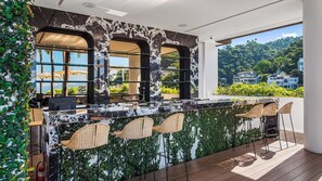 A bar area with a marble countertop, wicker chairs, and a view of the surrounding landscape.