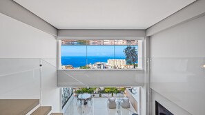 Ein modernes Interieur mit einem großen Fenster, das Meer und Gebäude zeigt.
