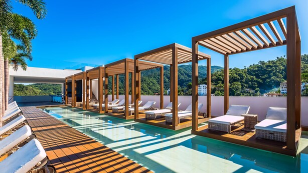 Área de piscina no terraço com pérgulas de madeira, espreguiçadeiras e vista desobstruída do verde ao redor.