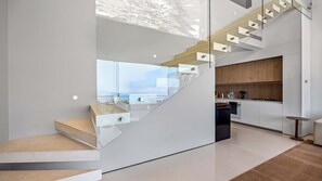 Un intérieur moderne avec un escalier menant à un balcon, un coin cuisine et un espace repas.