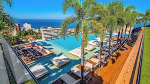 A rooftop pool area with lounge chairs, a sunbed, and a view of the ocean.