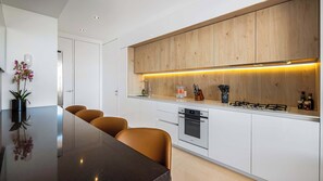 A modern kitchen with a central island, white cabinetry, and a wooden upper section.