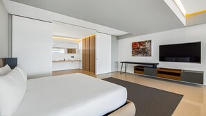 A modern hotel room with a large bed, a desk, a flat-screen TV, and a painting on the wall.