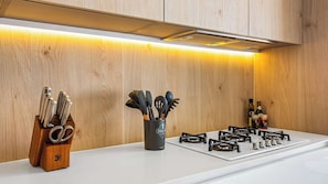 A modern kitchen with wooden cabinetry, a white countertop, a gas stove, and a utensil holder.
