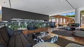 Un espace de détente extérieur moderne, doté de sièges, d’un bar et offrant une vue sur l’extérieur.
