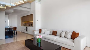 A modern living room with a white sofa, a coffee table, and a kitchen area in the background. - SoHo PV - PH 11 (Puerto Vallarta)