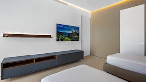 A modern bedroom with a bed, a built-in TV, a wall-mounted shelf, and a door. - SoHo PV - PH 11 (Puerto Vallarta)