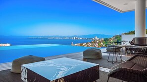 A modern outdoor seating area with a view of the sea and cityscape. - AlilaHolidays - Luxury Getaway in SOHO PV - 105 (Puerto Vallarta)