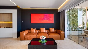 A modern living room with a leather sofa, a coffee table, and a large abstract painting on the wall. - AlilaHolidays - Luxury Getaway in SOHO PV - 105 (Puerto Vallarta)