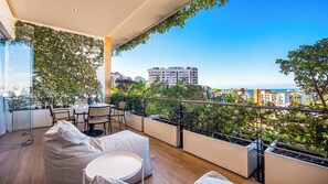A balcony with a view of the city, furnished with a table, chairs, and a sofa.