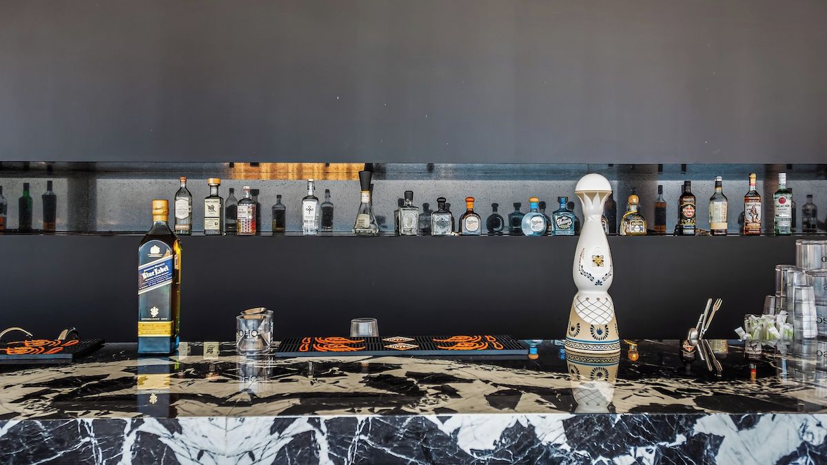 A bar area with a marble countertop, various liquor bottles, and a decorative vase.