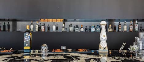 A bar area with a marble countertop, various liquor bottles, and a decorative vase.