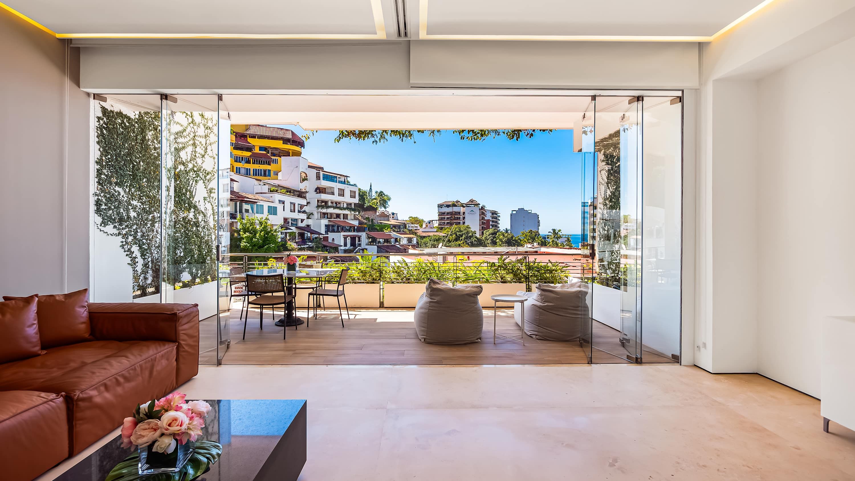 A modern living room with a large glass door leading to a balcony with a city view.