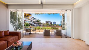 A modern living room with a large glass door leading to a balcony with a city view.