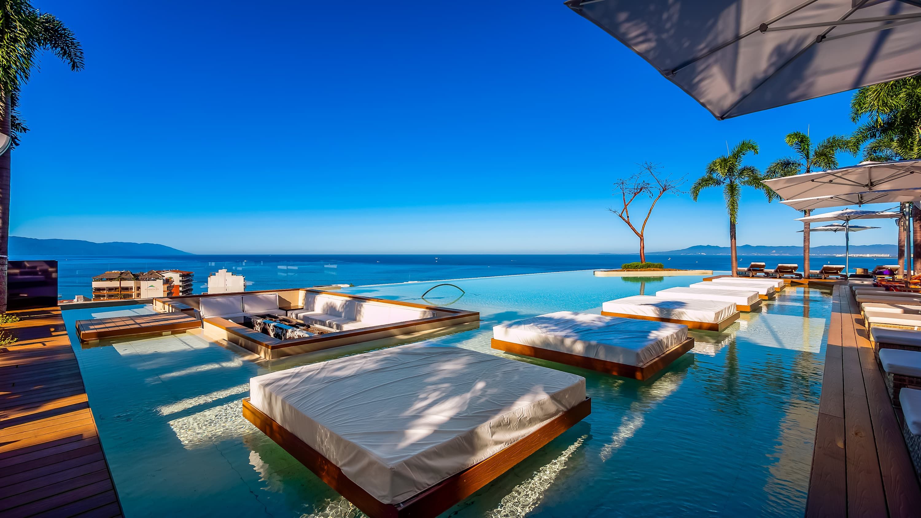 Une piscine à débordement avec des chaises longues et une vue sur l’océan.