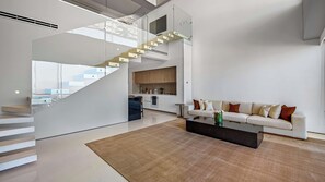 Un espace de vie moderne comprenant un escalier, une cuisine et un coin salon.