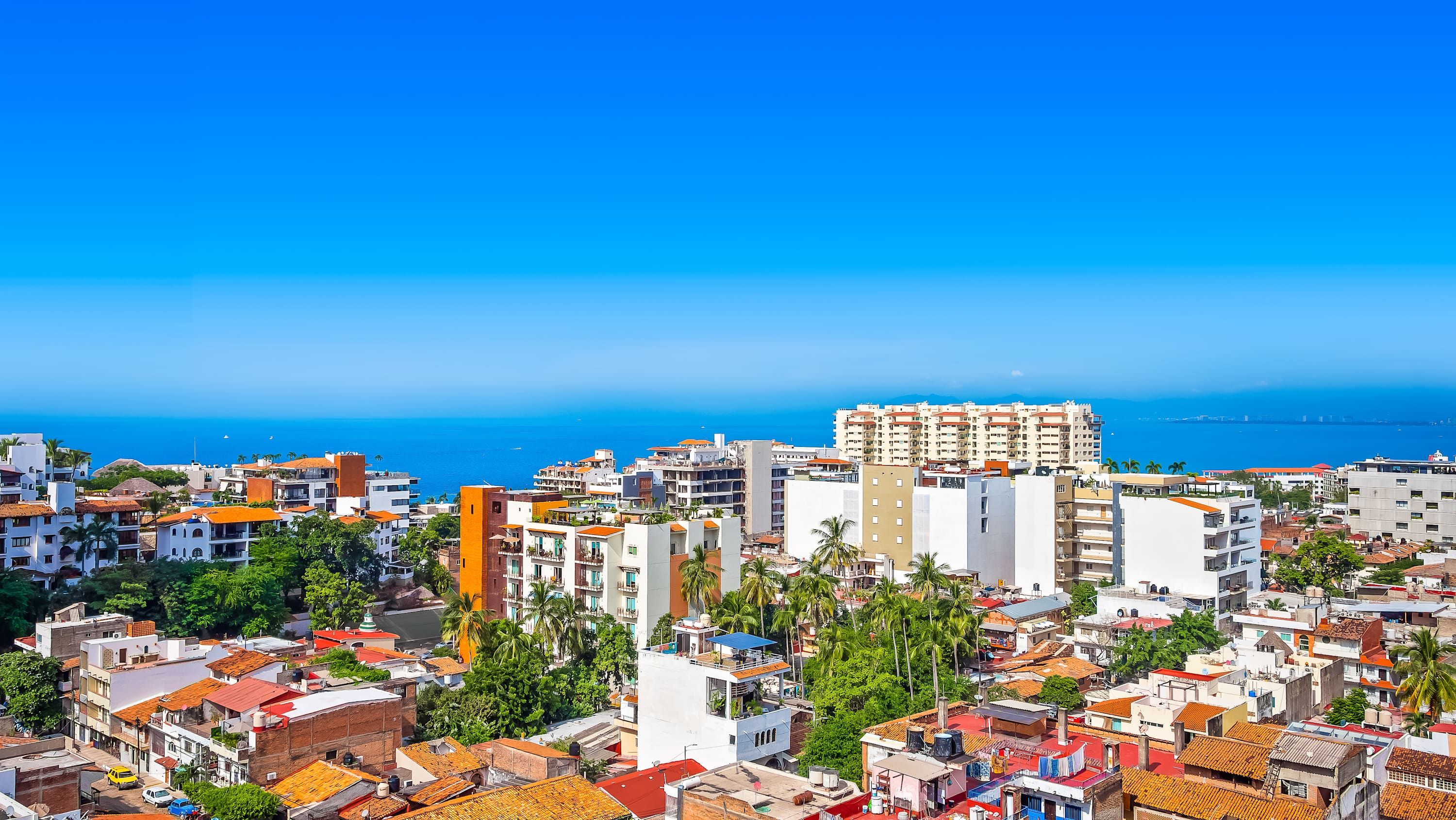 Un paisaje urbano costero con una mezcla de edificios residenciales y comerciales, incluyendo un hotel destacado con varios pisos y balcones.