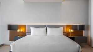 Ein modernes Hotelzimmer mit einem großen Bett, zwei Nachttischen mit Lampen und einem Kopfteil mit integrierter Beleuchtung.