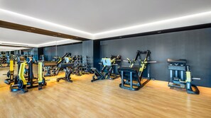 Une salle de sport moderne équipée de divers appareils d’exercice et dont les murs sont recouverts de miroirs.