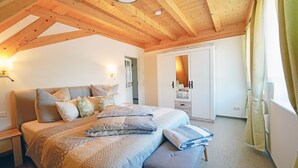 Un dormitorio con una cama grande, vigas de madera en el techo, un vestidor y un baño con cortina de ducha.