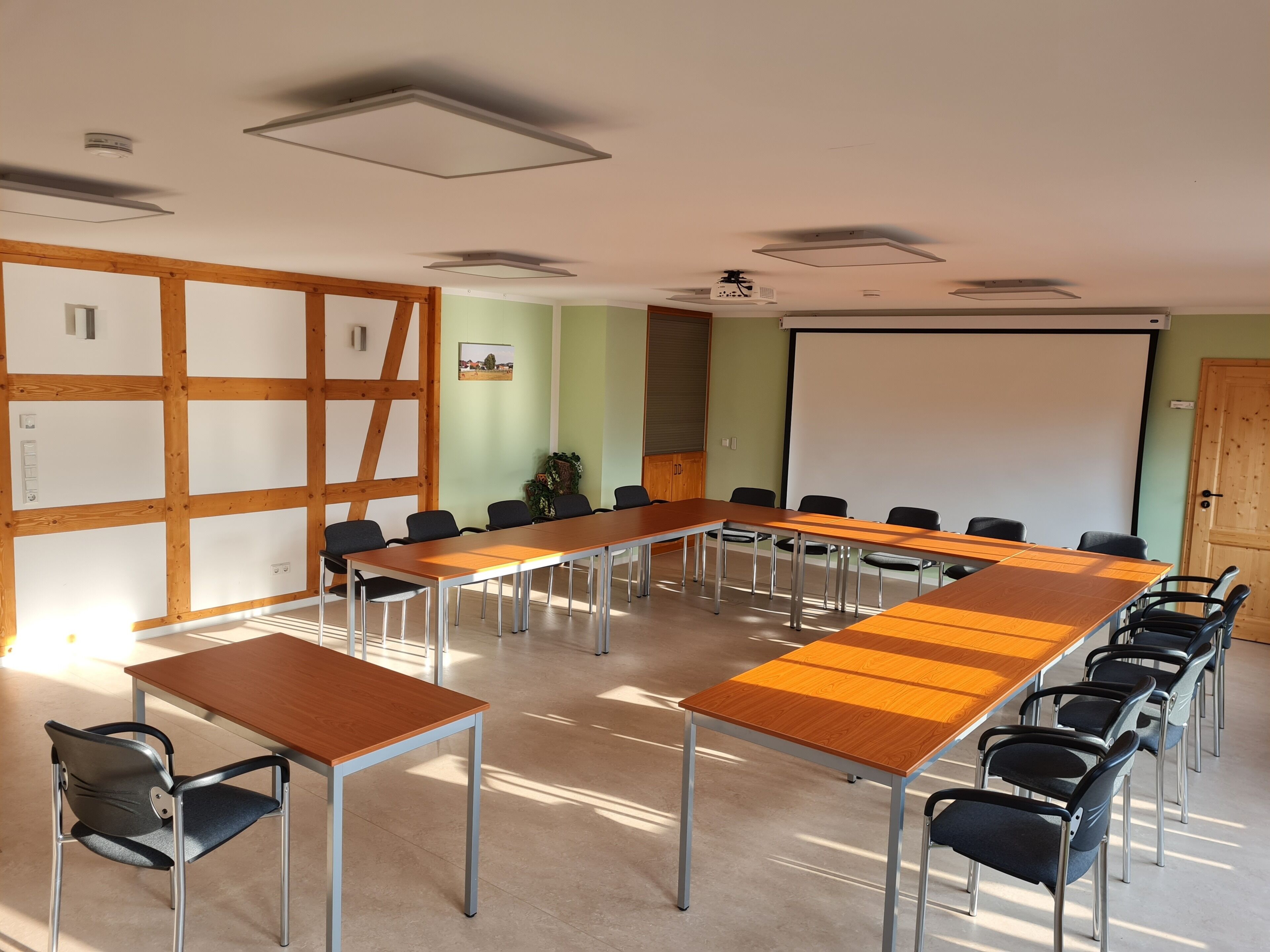 A conference room with a long table, chairs, a projector screen, and a whiteboard.