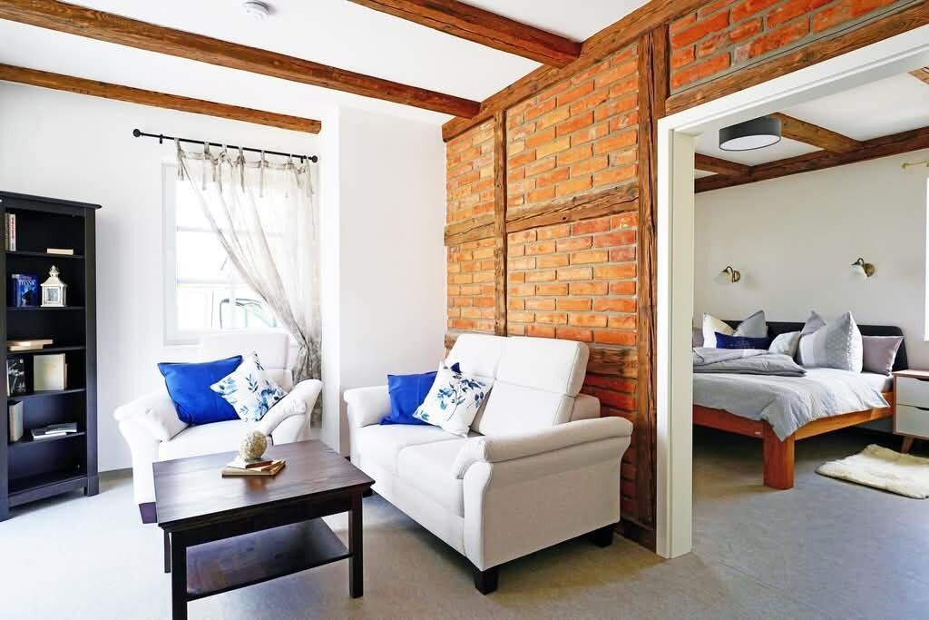 Una sala de estar con un sofá blanco, una mesa de centro y un separador de ladrillo.
