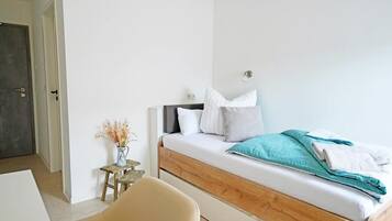 Ein Schlafzimmer mit einem Bett, einem kleinen Tisch mit einer Vase und einer Tür.