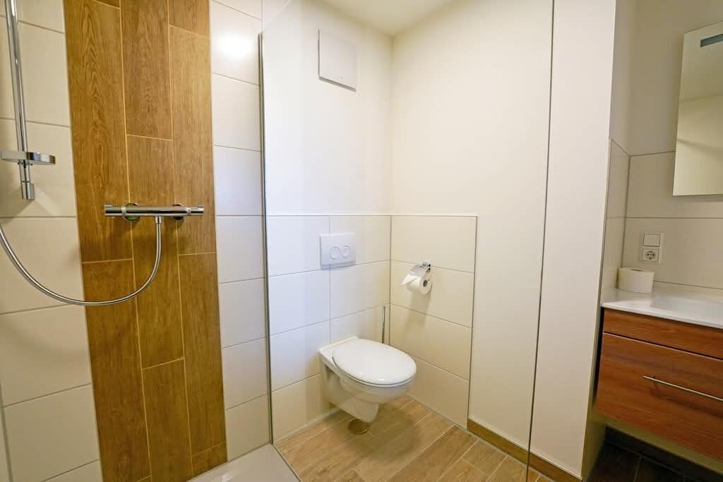 A small bathroom with a toilet, a shower, and a wooden door.