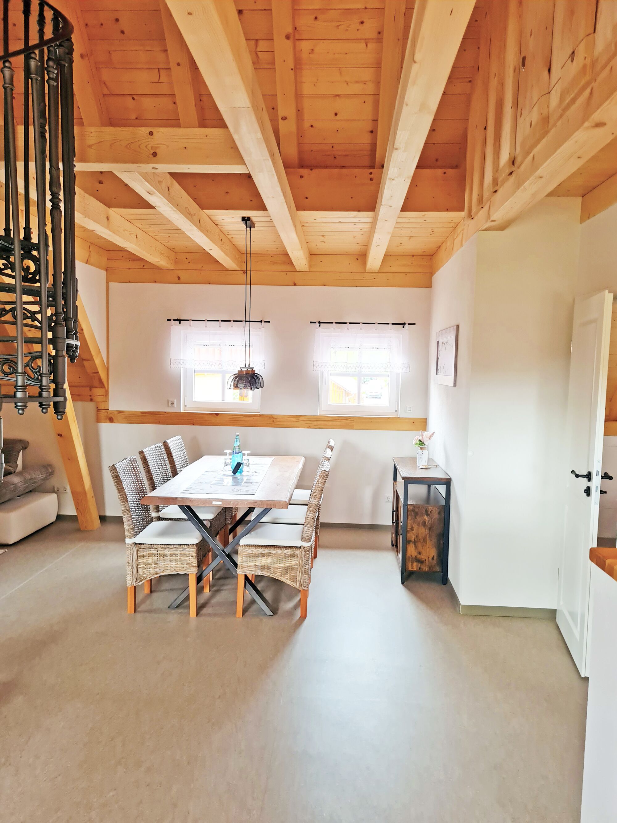 Un coin repas avec une table et des chaises en bois, un escalier et une porte blanche.