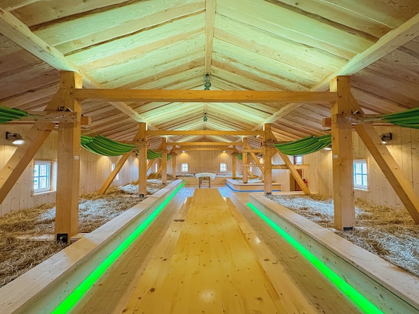 A barn with wooden beams, hay on the floor, and a central aisle.
