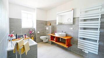 A modern bathroom with a bathtub, toilet, sink, and towel rack.