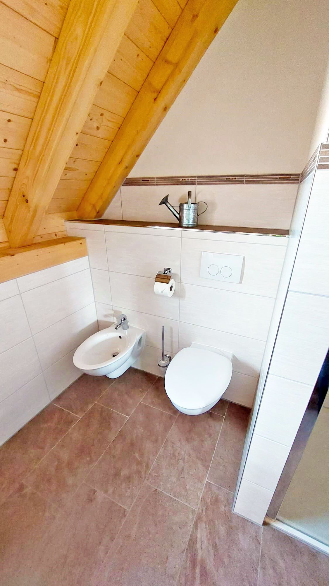 Un baño con techo de madera, dos inodoros, un lavabo y una ducha.