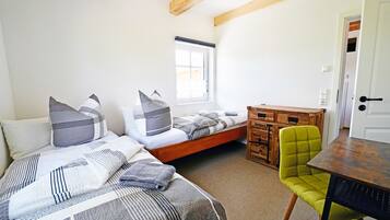 A bedroom with two beds, a window, a desk, and a chair.