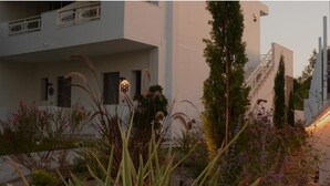 Ein modernes Gebäude mit weißer Fassade, einer Treppe und einem Garten mit verschiedenen Pflanzen.