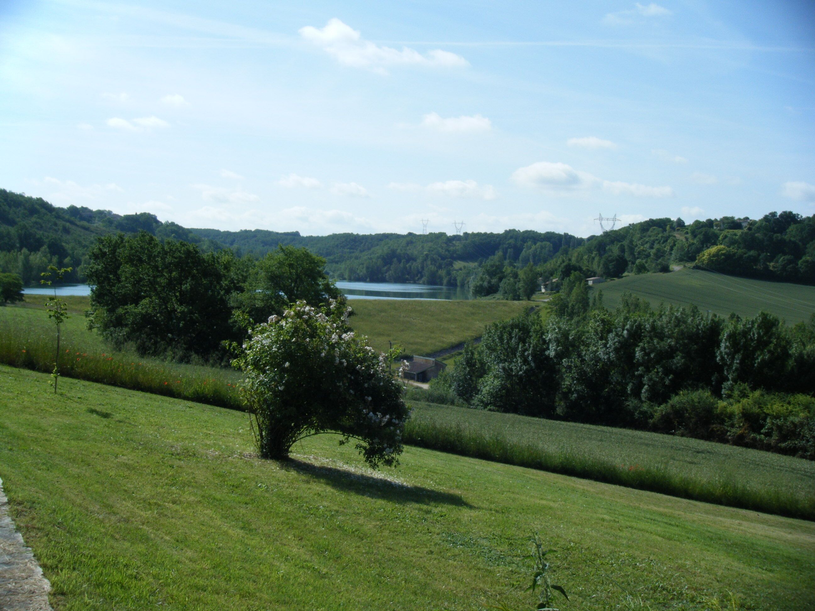 A rural landscape with a lake, rolling hills, and a clear sky.