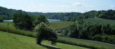 A rural landscape with a lake, rolling hills, and a clear sky.