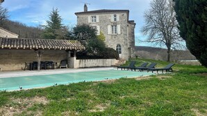 A stone building with a swimming pool, outdoor seating, and a view of the surrounding landscape. - Private swimming pool - Charming Quercy stone house (Roquecor)