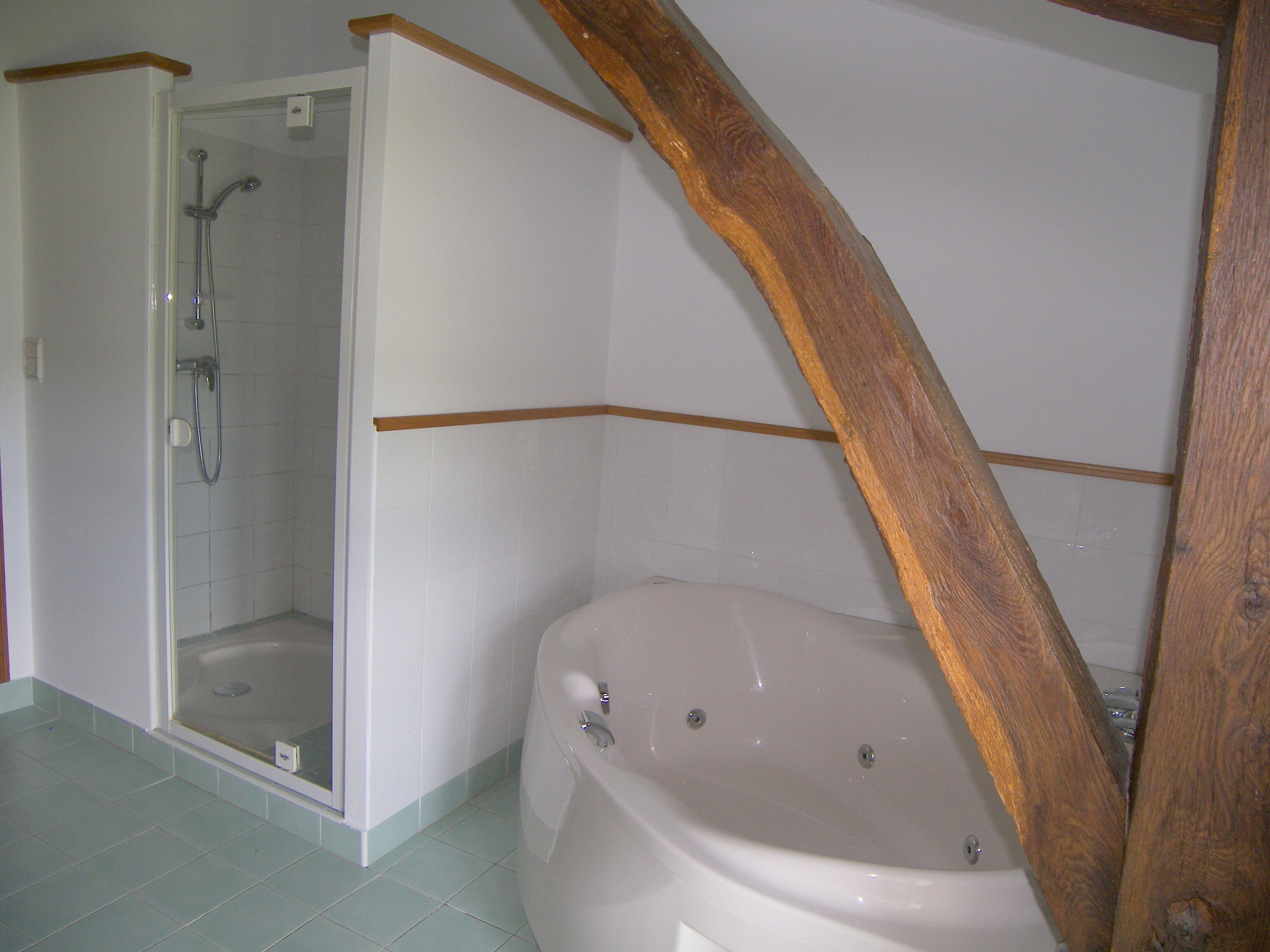 Un baño con ducha, bañera y una viga de techo de madera.