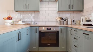 A kitchen with light blue cabinets, a Bosch oven, and a white tiled backsplash. - Brooklands Farm Cottage (Biggleswade)