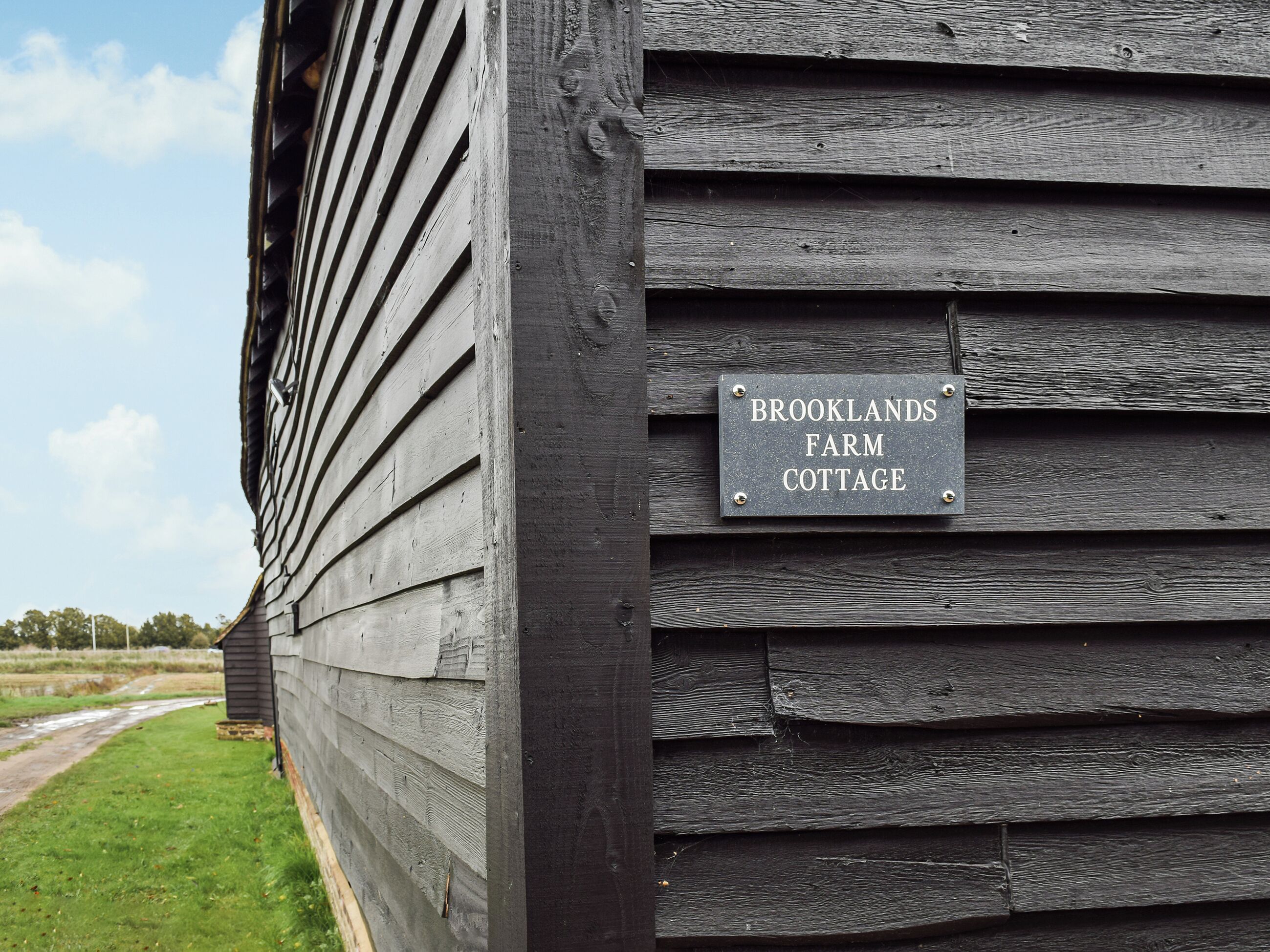 A wooden building with a sign reading "Brooklands Farm Cottage."