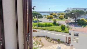A view from a window overlooking a residential area with a street, greenery, and a body of water in the distance. - Porto Apartments - La Caletta (Siniscola)