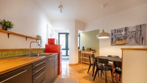 A modern kitchen with a wooden countertop, a red refrigerator, and a dining area with a table and chairs. - GuestReady - A comfortable stay in Lisbon (Lisbon)