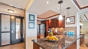 A modern kitchen with granite countertops, wooden cabinets, and a central island with fruit.