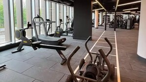 Et fitnesscenter med træningsudstyr, store vinduer og moderne belysning.