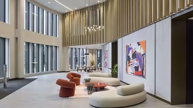 En rummelig lobby med moderne møbler, store vinduer og abstrakt kunst på væggene.
